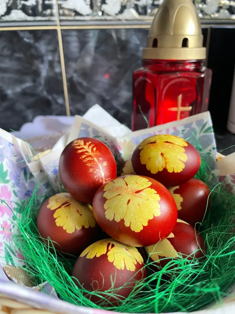 Red Easter eggs decorated with yellow leaf patterns nestled in green grass