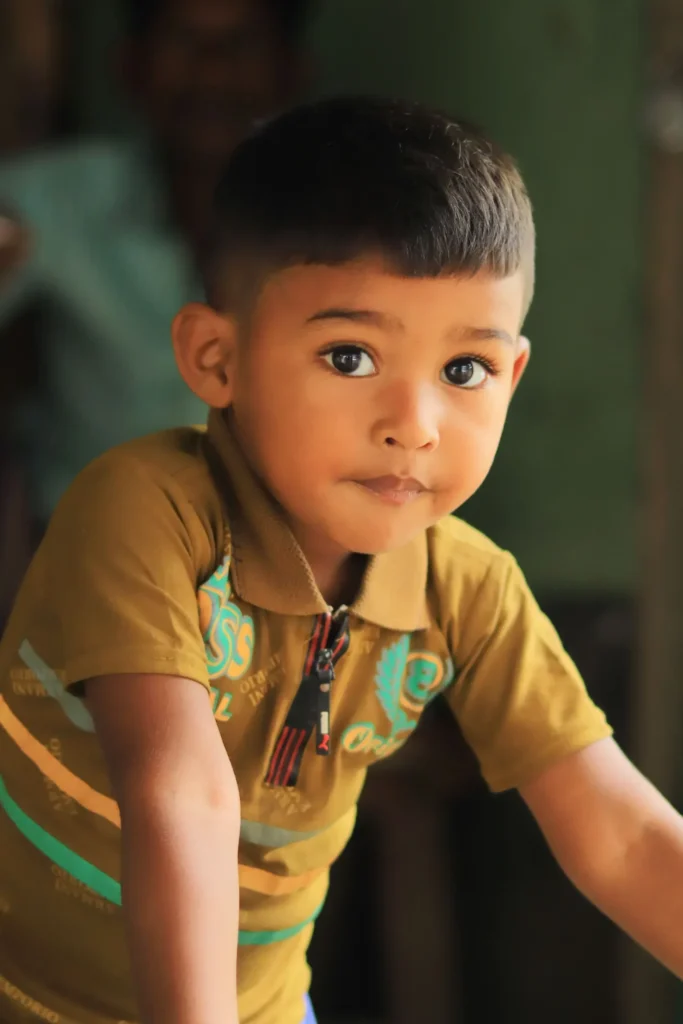 Young boy in a tan polo shirt looking directly at the camera